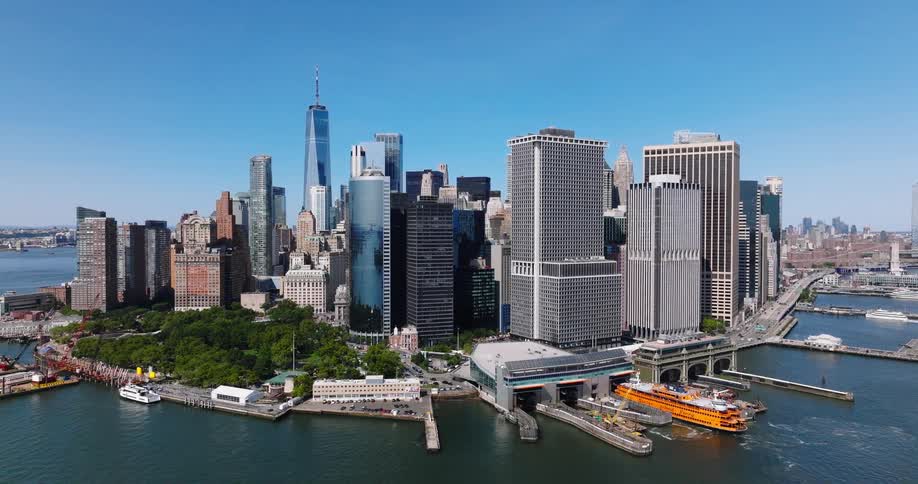 Aerial view slowly pushing in towards the Lower Manhattan skyline and the Staten Island Ferry terminal on a bright sunny day