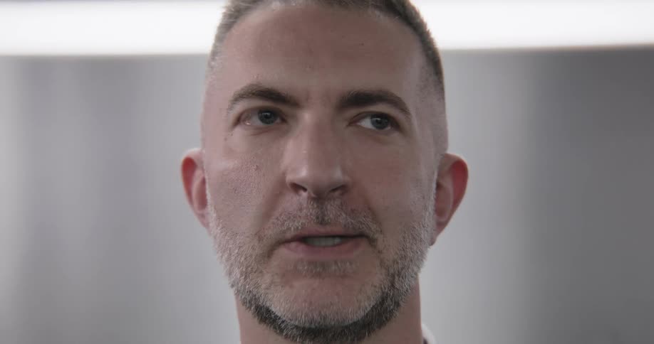 A close-up of a professional man with a beard listening and reacting with a range of facial expressions during a conversation