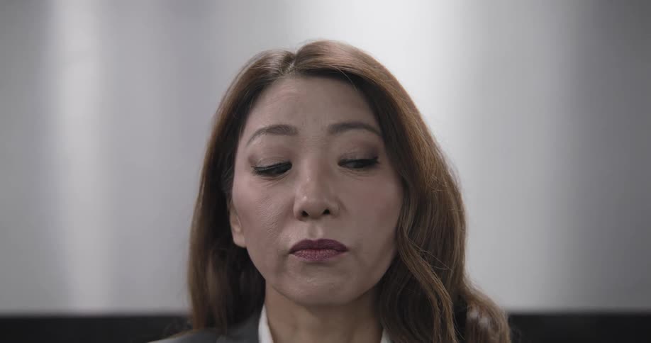 A close-up shot shows a serious businesswoman looking up and rolling her eyes in exasperation and annoyance
