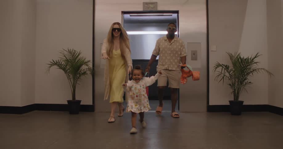 A joyful family with young children happily runs out of an elevator in slow motion, excited for their vacation day