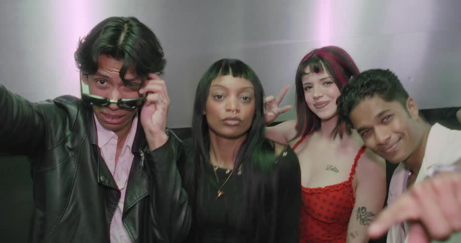 A diverse group of trendy young friends take a fun selfie video in an elevator, posing and smiling for the camera on a night out