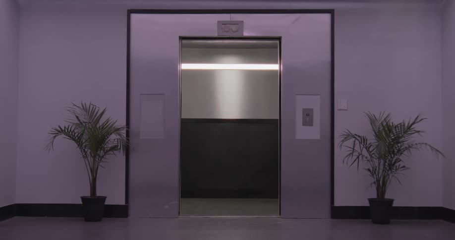 Modern stainless steel elevator doors open and close in a dimly lit, purple-hued hallway