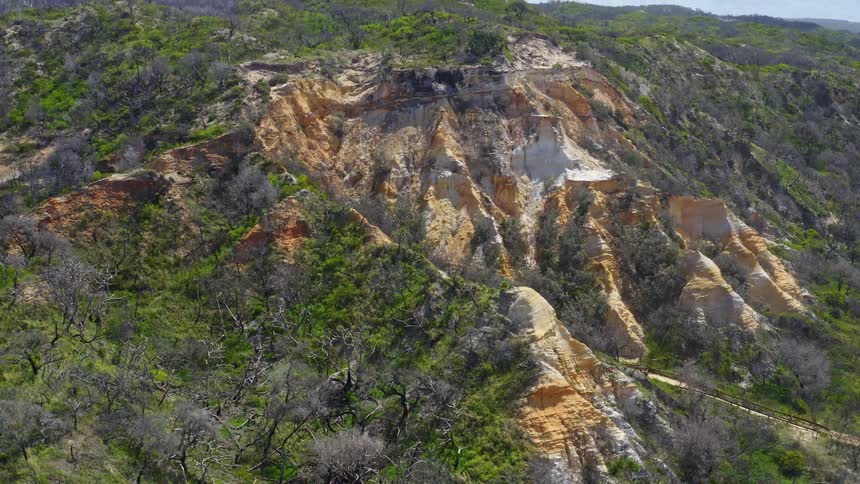 Slow zoom out aerial reveal of the stunning colorful sand pinnacles on K'gari Fraser Island, Australia