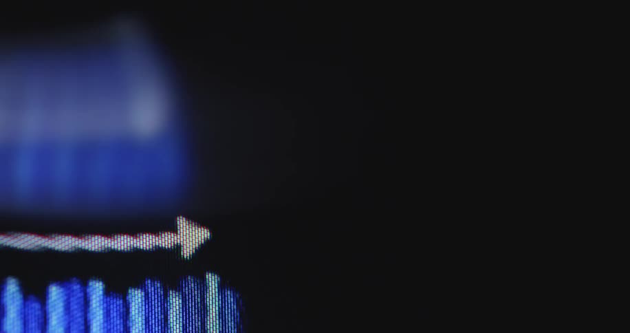 A macro shot of a blue bar graph on a computer screen with a white arrow indicating an upward trend of growth and success