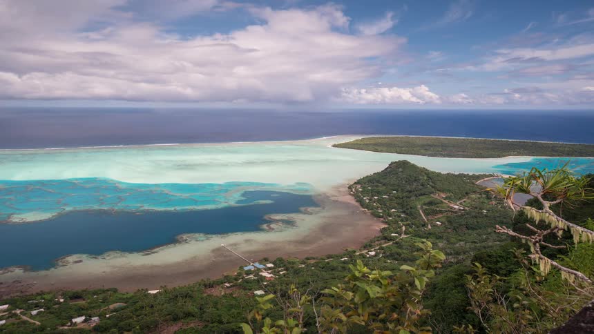 A breathtaking time-lapse from a high vantage point overlooking the vibrant turquoise lagoon and lush green landscape of a tropical island