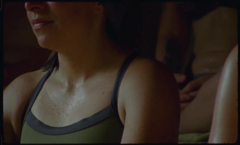 Close-up of a woman in a sports top sweating and relaxing in a dark, warm sauna