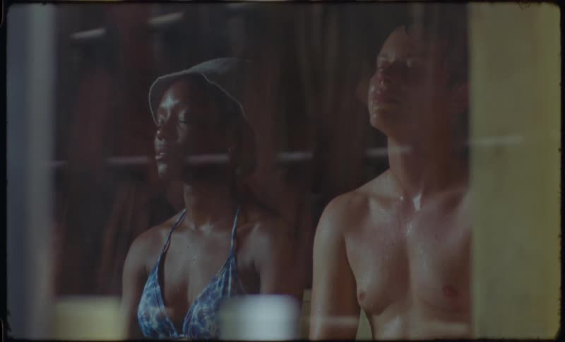 Vintage film shot of a man and woman relaxing with eyes closed in a hot, steamy sauna