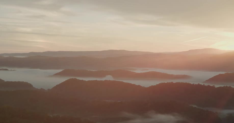 A serene time-lapse reveals a golden sunrise over a vast mountain range with a sea of fog filling the valleys