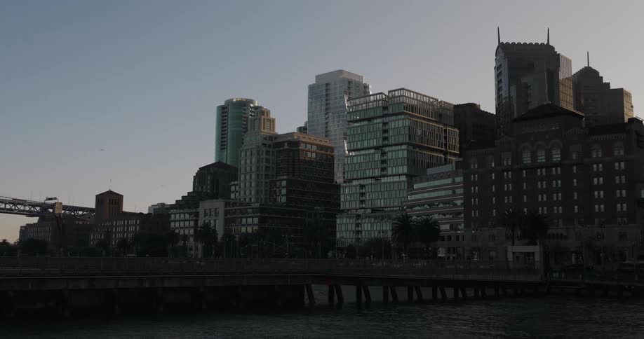 A serene, static wide shot of the San Francisco skyline from across the bay at sunrise as a bird flies by