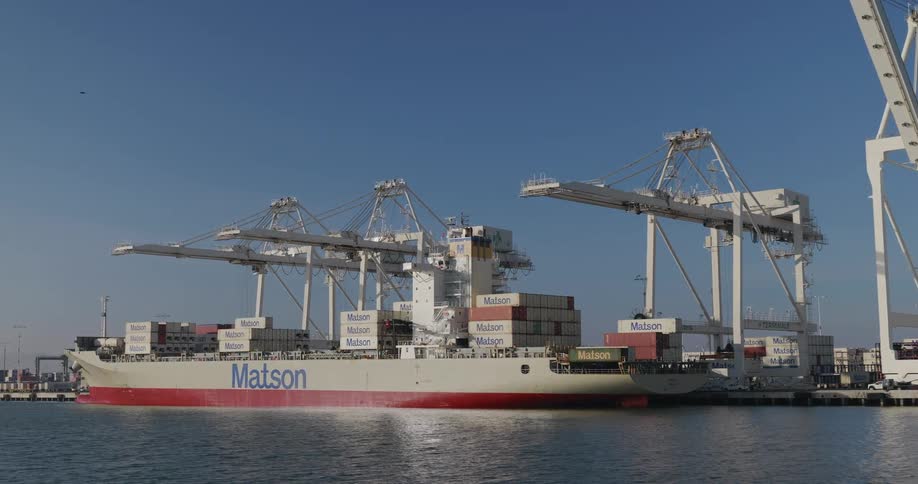 Time-lapse of cranes loading and unloading shipping containers from a large cargo ship docked at a busy industrial port