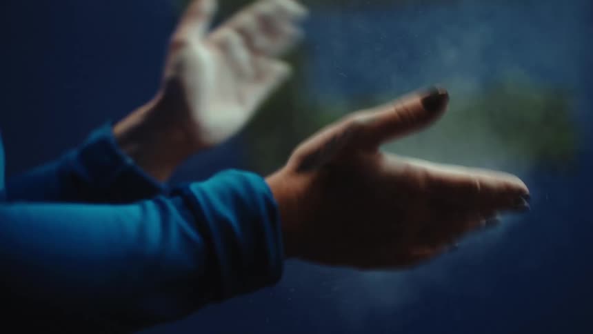 A close-up view of an athlete's hands clapping together, creating a cloud of white chalk dust