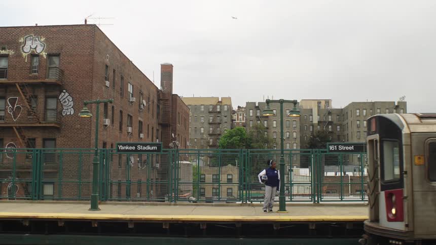A woman waits on the platform at the 161st Street-Yankee Stadium subway station as a train arrives in the Bronx, New York City