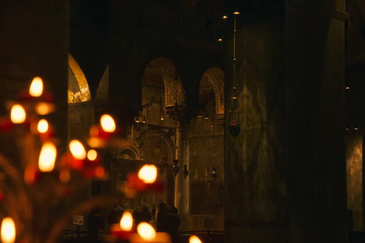 Softly glowing prayer candles illuminate the dark and ancient interior of a historic cathedral