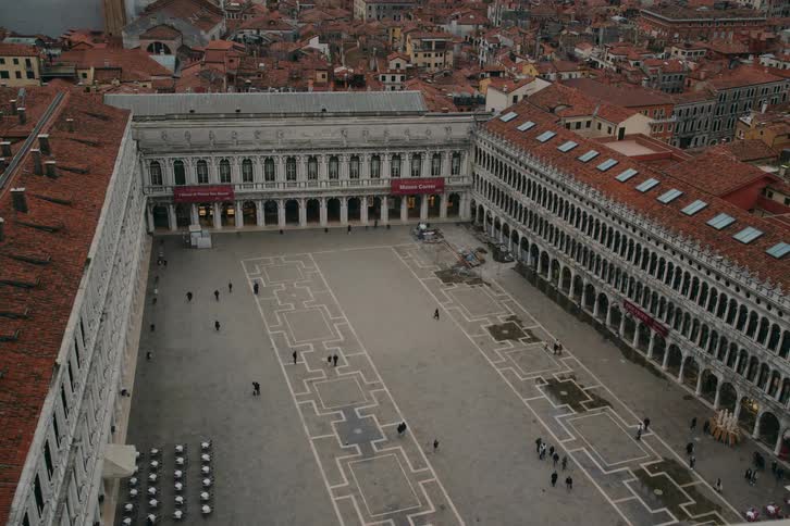 A high-angle perspective captures the vast, sparsely populated Piazza San Marco in Venice on an overcast day