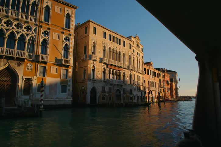 Historic Venetian architecture glows in the warm golden hour light during a scenic boat ride along the Grand Canal in Italy