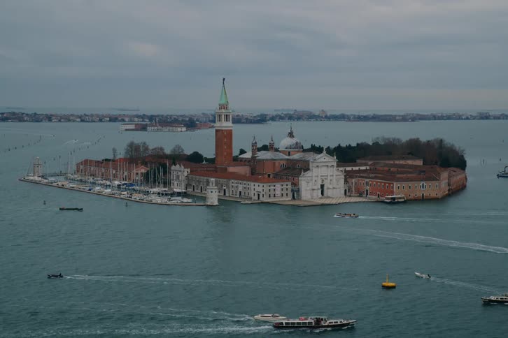 Boats navigate the waters around the historic island of San Giorgio Maggiore in Venice under an overcast sky
