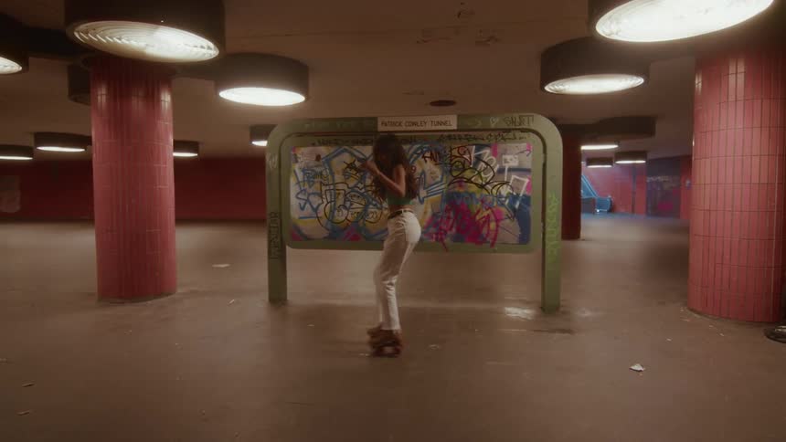 A stylish young woman grooves on roller skates in a gritty, graffiti-covered underground station