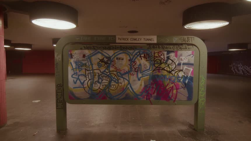 A slow zoom out from a graffiti-covered sign in the empty and gritty Patrick Cowley Tunnel underpass
