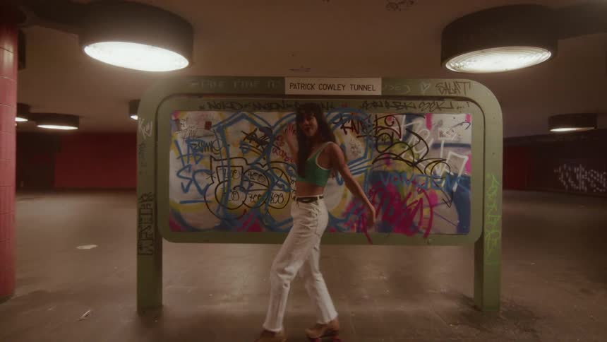 A woman dances gracefully on roller skates through an empty, graffiti-covered underground tunnel
