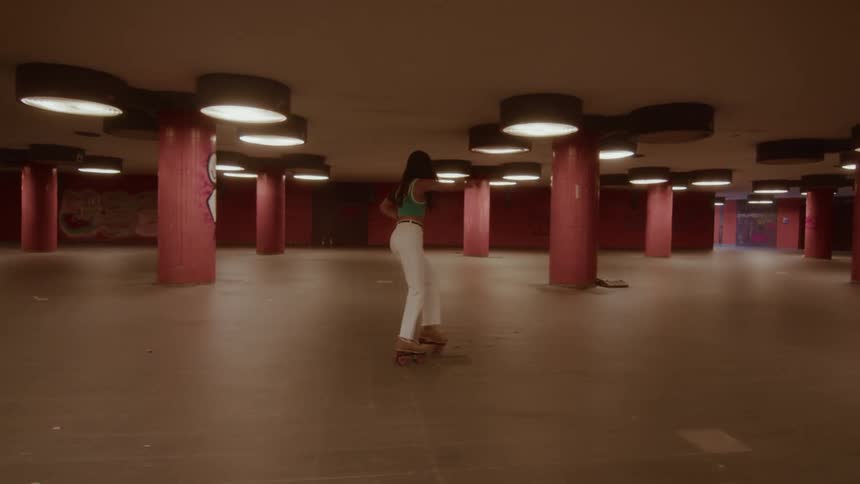 Tracking shot of a stylish woman gracefully roller skating through a deserted underground subway station