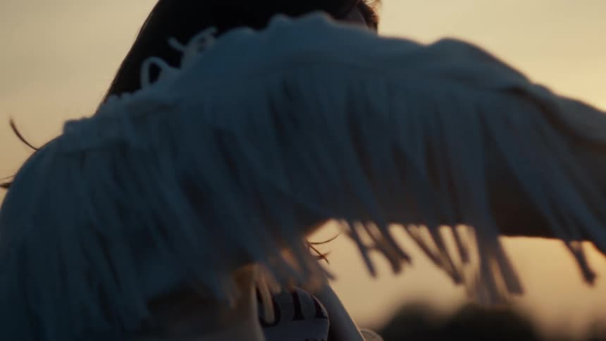 Slow motion close-up of a serene woman with her eyes closed, basking in the warm golden hour light of the setting sun