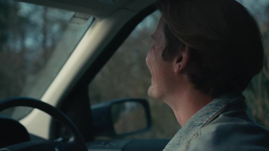 Side profile of a handsome man smiling contentedly while driving his car