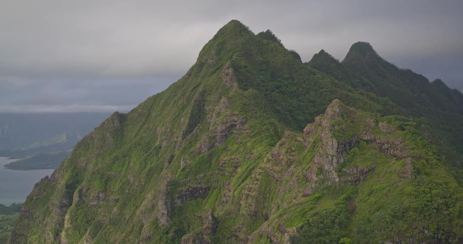 Slow aerial push-in shot of the dramatic, lush green mountain ridges of Oahu, Hawaii, on a cloudy day