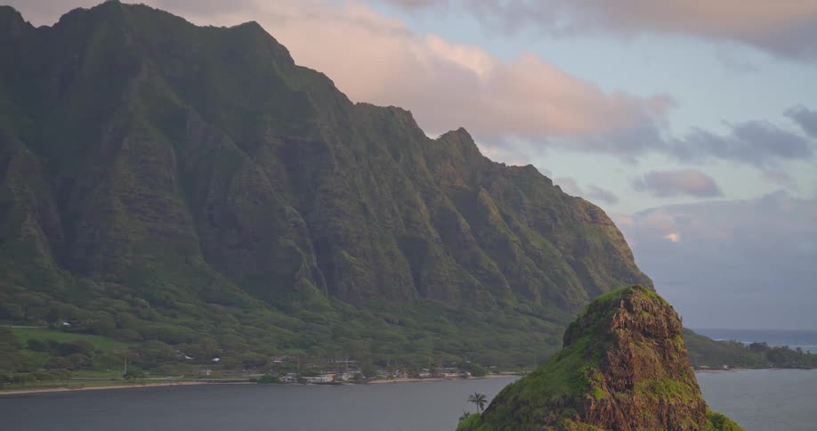 Epic aerial footage pulls back from Mokoli'i Island to reveal the dramatic and lush Kualoa mountain range on Oahu at sunrise