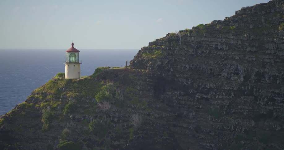 A scenic zoom-out reveals a picturesque lighthouse standing watch on a dramatic, rugged cliff overlooking the vast blue ocean