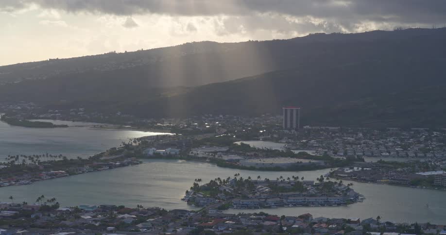 Golden sun rays beam down through dramatic clouds over the coastal community of Hawaii Kai on the island of Oahu
