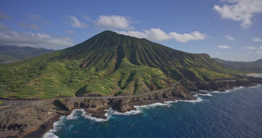A stunning aerial view of the lush green mountainside of Koko Head crater on the rocky coast of Oahu, Hawaii