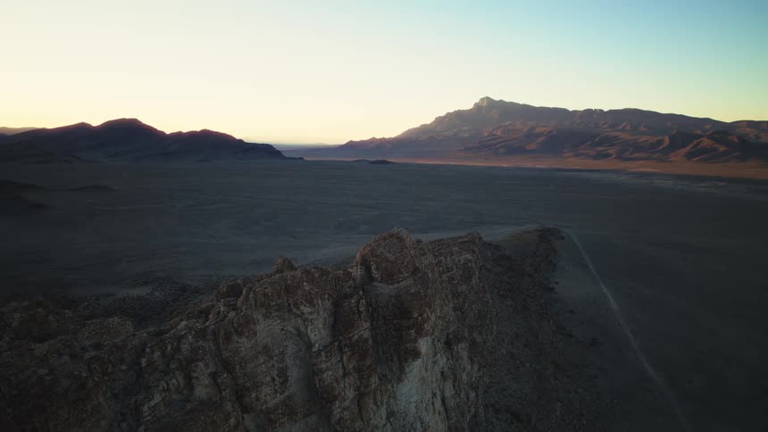 Epic aerial footage captures the serene beauty of a desert mountain landscape during a warm and tranquil sunrise