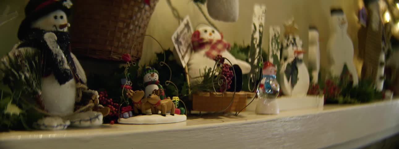 A woman puts christmas decorations on a fireplace mantle