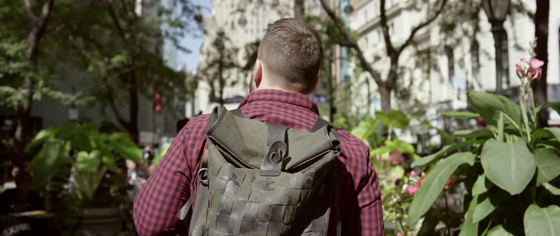 A man with a backpack walks through a city