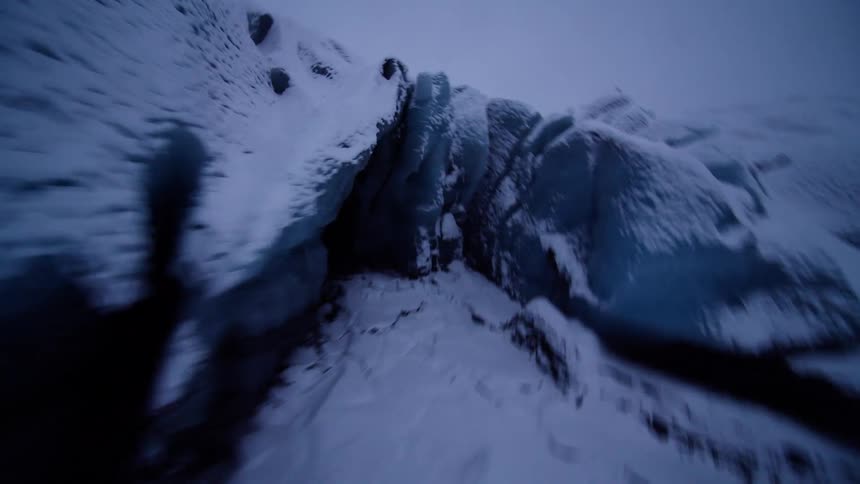 A thrilling FPV drone flight navigates the icy crevasses of a vast, snow-covered glacier