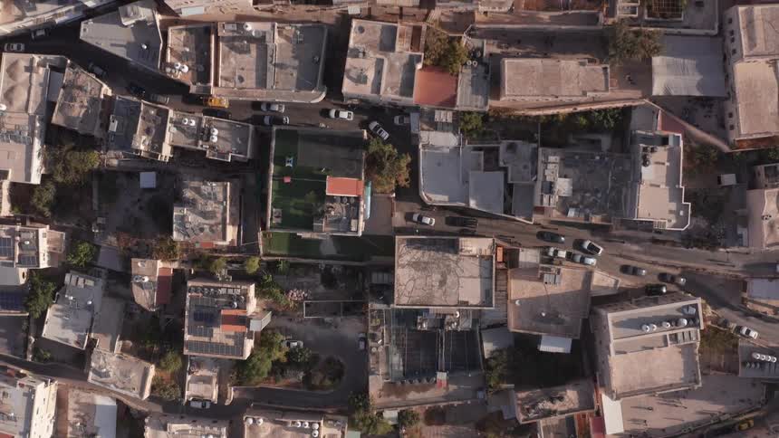 An aerial top-down view slowly rises to reveal the dense rooftops and narrow streets of an ancient city