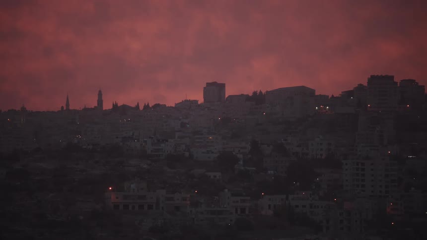 A wide shot of a sprawling city skyline at dusk under a dramatic, fiery red sky