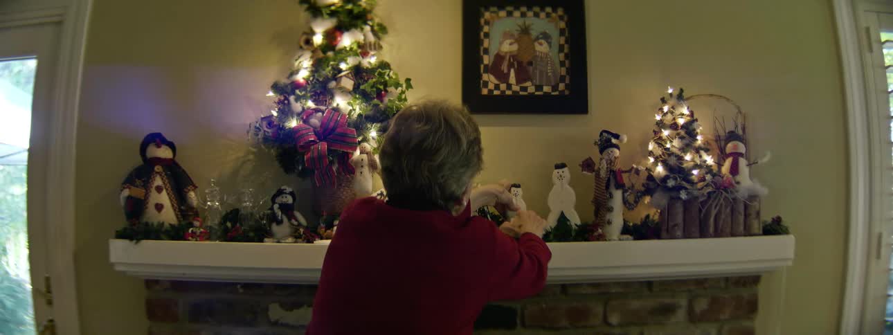 Woman adjusts christmas decorations on mantel shelf