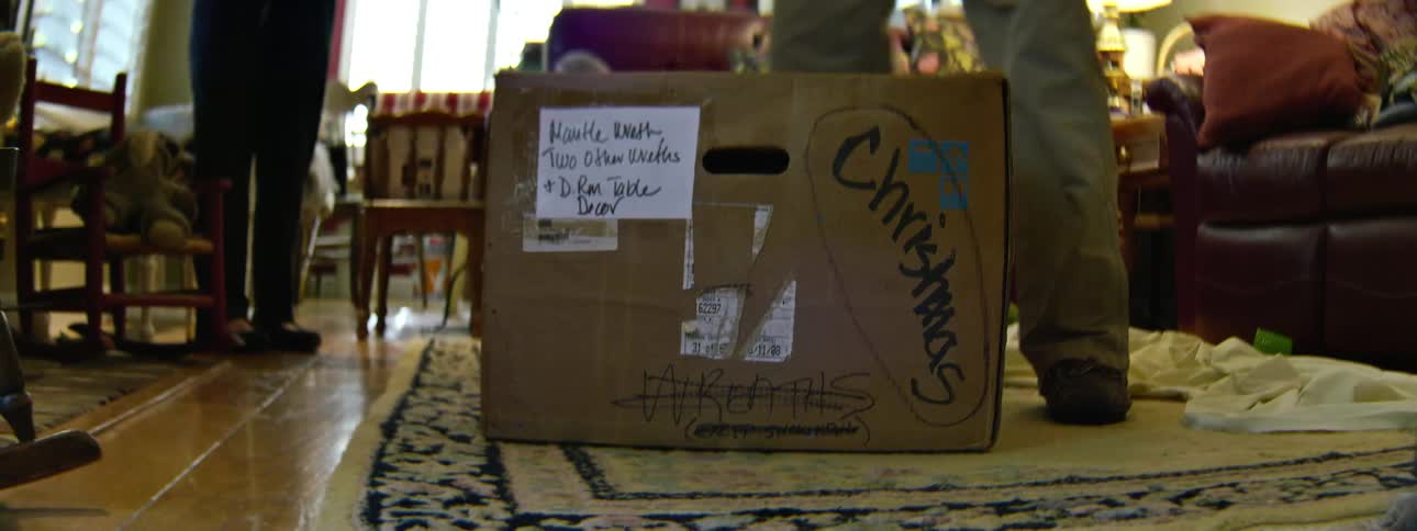 A man sets down a box labeled christmas