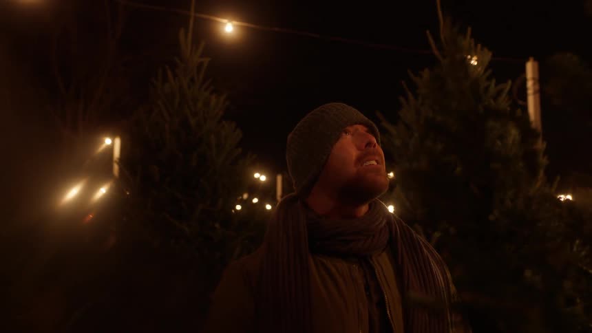 A man looks up smiling at night