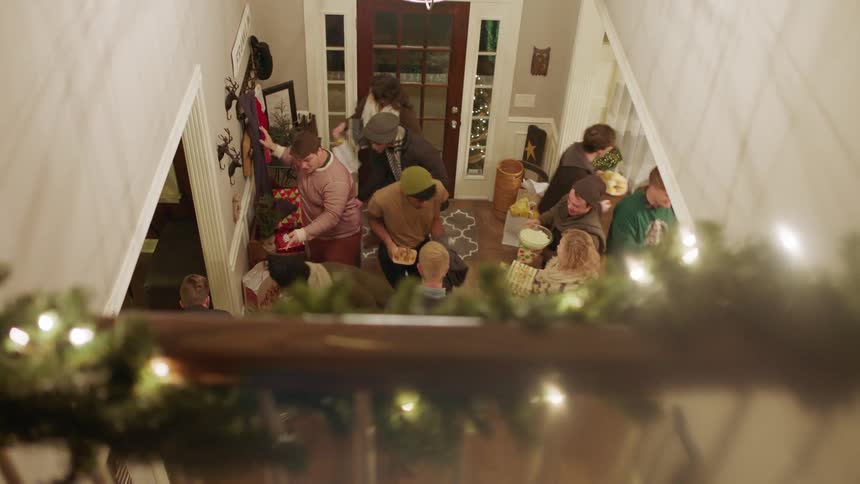 A group of people greet each other in a house foyer at christmas