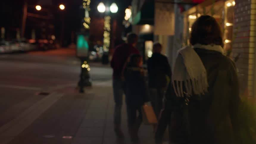 A family walks on a city sidewalk at christmastime