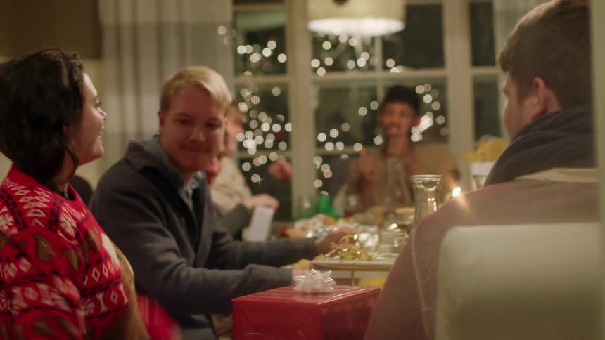 A woman putting on a sweater as she and everyone else sits around a table