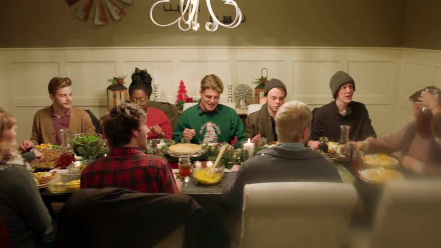 A woman walks into a dining room full of people eating together