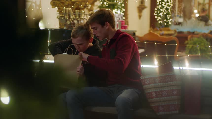 Two boys looking in a bag while sitting outside on a bench