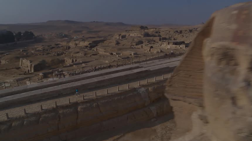 An aerial shot reveals a young boy running past the majestic Great Sphinx of Giza in the vast Egyptian desert