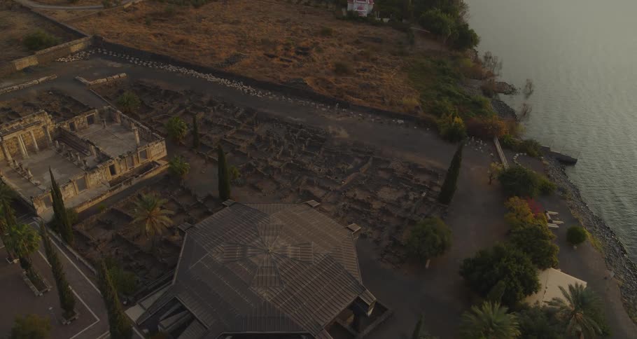An aerial perspective reveals the ancient town of Capernaum, including its historic synagogue, nestled by the Sea of Galilee at dusk