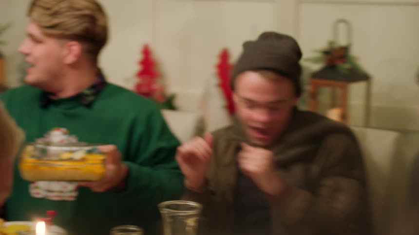 A family passes around dishes of food at a table, and talk