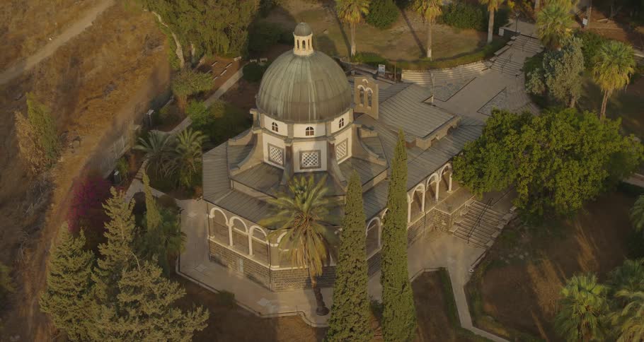 Slowly rotating aerial shot of the magnificent, domed Church of the Beatitudes in Israel during a golden sunrise