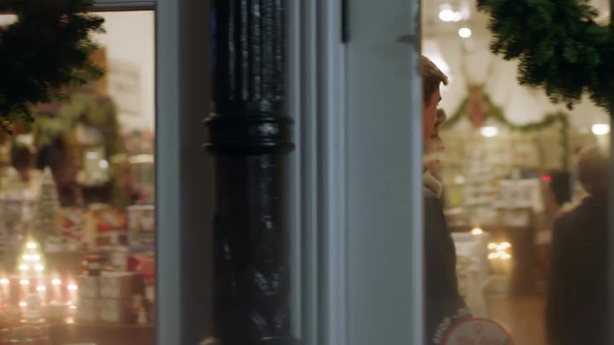 A woman and children enter a shop decorated for christmas